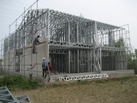 a group of people working on a steel frame for a house