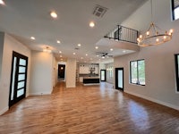 an empty living room with hardwood floors and a chandelier