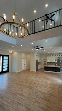 a large living room with hardwood floors and a chandelier