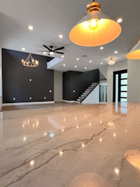 a white kitchen with marble counter tops and light fixtures