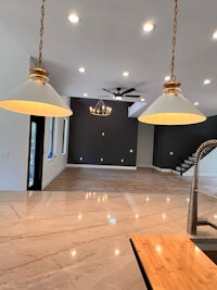 a kitchen with marble counter tops and two pendant lights